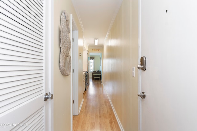 hallway with light hardwood / wood-style flooring and ornamental molding