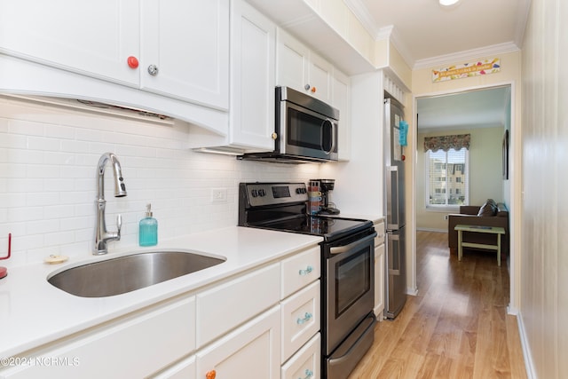 kitchen with crown molding, sink, light hardwood / wood-style flooring, appliances with stainless steel finishes, and white cabinetry