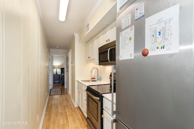 kitchen with white cabinets, crown molding, decorative backsplash, appliances with stainless steel finishes, and light hardwood / wood-style floors