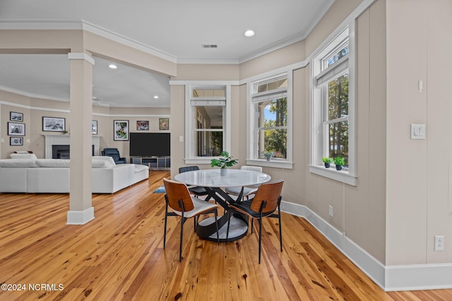 dining area with decorative columns, light hardwood / wood-style flooring, and crown molding