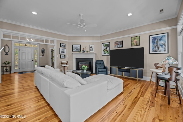 living room with ceiling fan with notable chandelier, light hardwood / wood-style floors, and crown molding