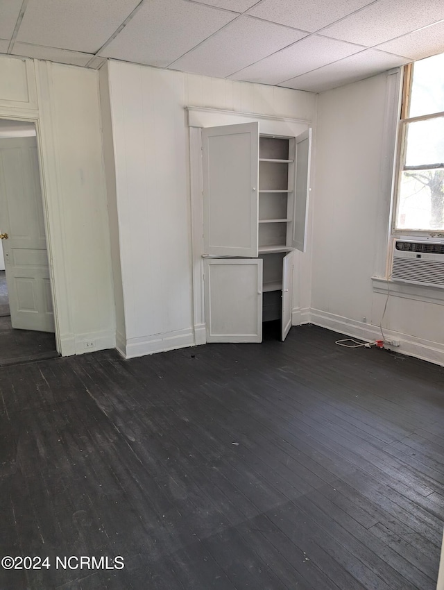 unfurnished bedroom with cooling unit, dark wood-type flooring, and a paneled ceiling