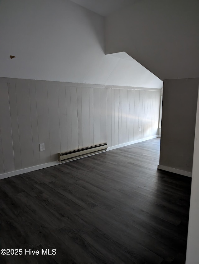 additional living space featuring a baseboard radiator, vaulted ceiling, and dark wood-type flooring