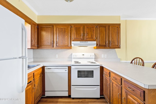 kitchen with kitchen peninsula, hardwood / wood-style flooring, crown molding, sink, and white appliances