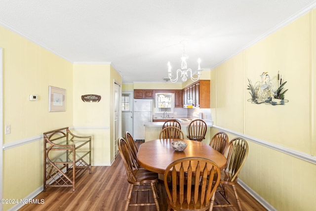 dining area with sink, hardwood / wood-style floors, crown molding, and an inviting chandelier