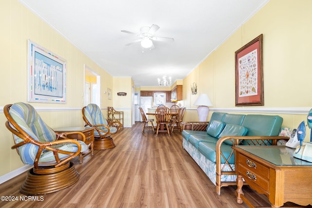 living room featuring ornamental molding, ceiling fan with notable chandelier, and light wood-type flooring