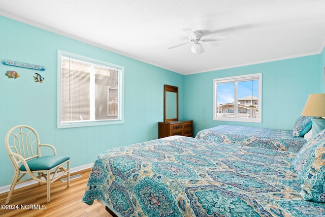 bedroom with ornamental molding, light hardwood / wood-style flooring, and ceiling fan