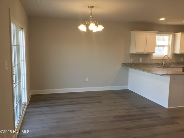 kitchen with sink, white cabinetry, plenty of natural light, dark hardwood / wood-style floors, and light stone counters