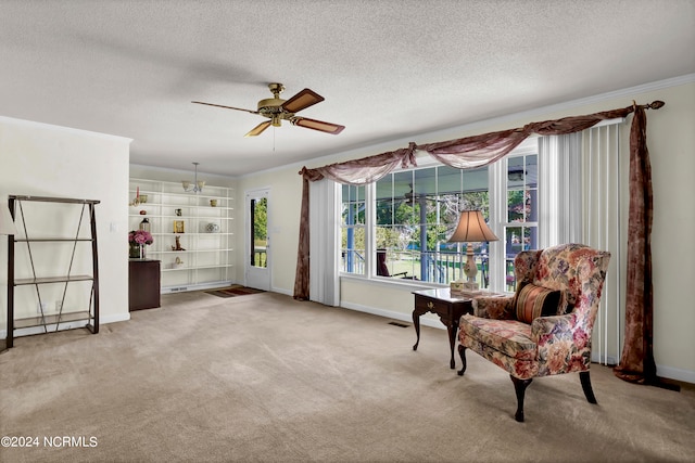 sitting room with ceiling fan, a textured ceiling, ornamental molding, and light colored carpet