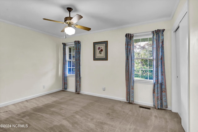 empty room featuring ceiling fan, ornamental molding, and light colored carpet