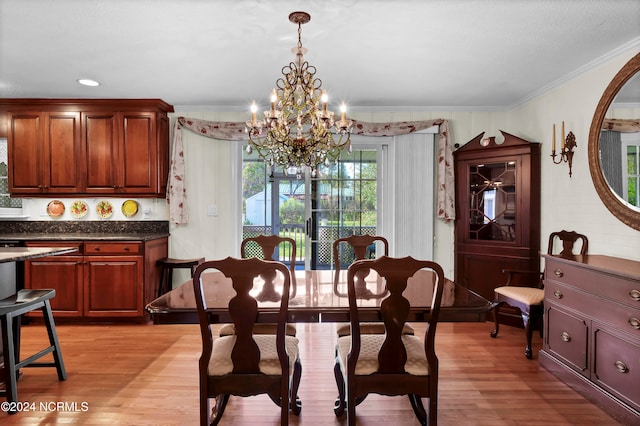 dining room with light hardwood / wood-style flooring, crown molding, and an inviting chandelier