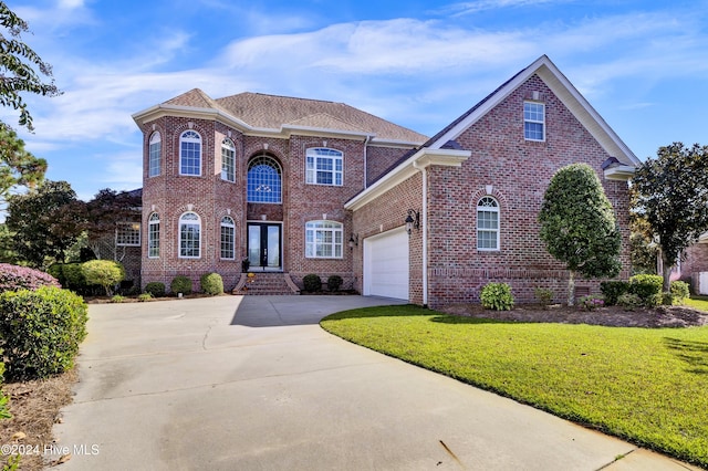 view of front of house featuring a front yard, roof with shingles, concrete driveway, a garage, and brick siding