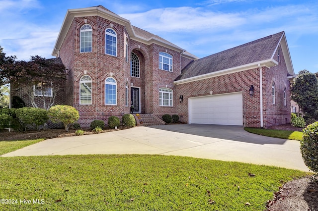 traditional-style house with concrete driveway, an attached garage, brick siding, and a front yard