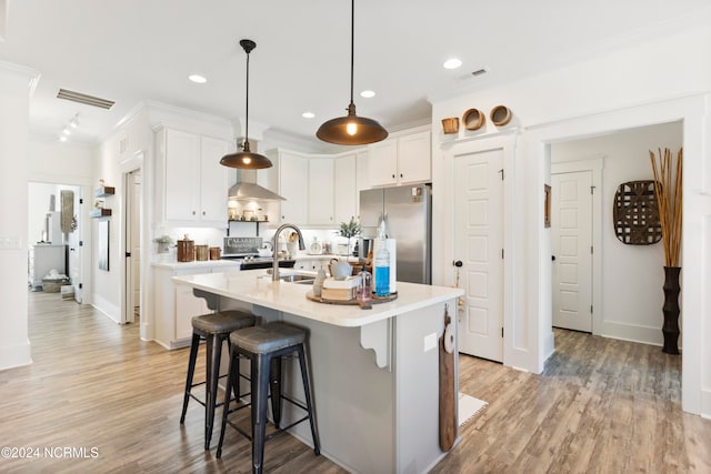 kitchen featuring visible vents, a breakfast bar, light countertops, and freestanding refrigerator