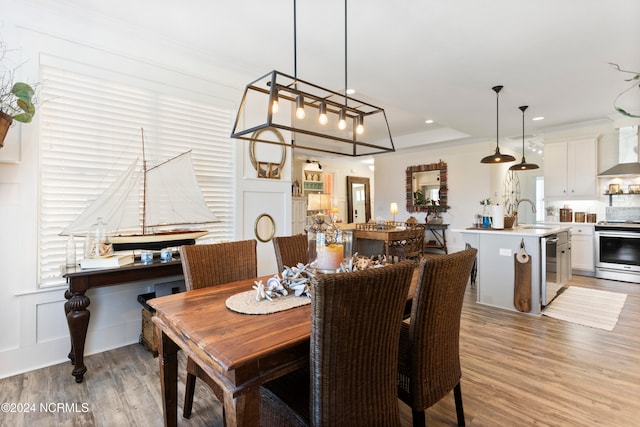 dining area featuring a decorative wall, recessed lighting, light wood-type flooring, and ornamental molding