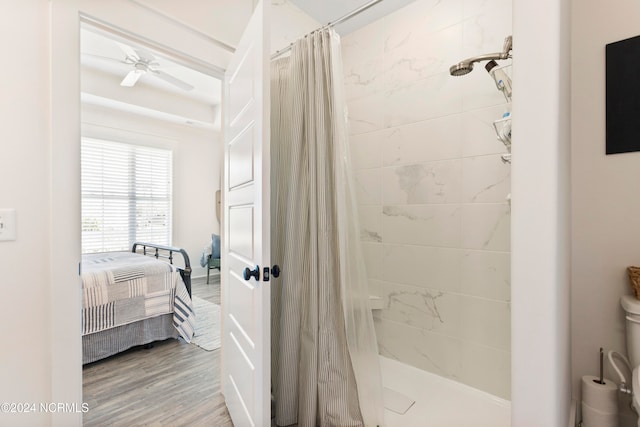 ensuite bathroom featuring ceiling fan, ensuite bath, wood finished floors, and a shower stall