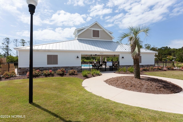 view of front facade featuring metal roof, driveway, a front lawn, and fence