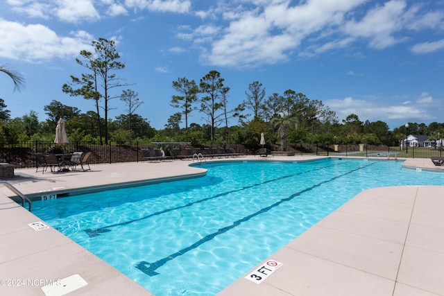 community pool with a patio area and fence