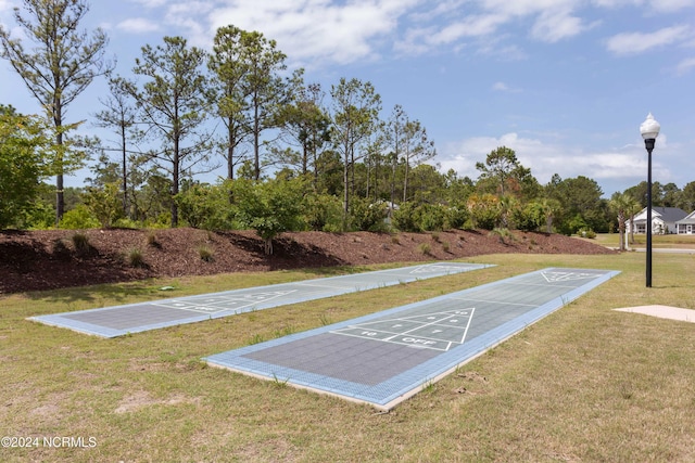 view of home's community with shuffleboard and a yard