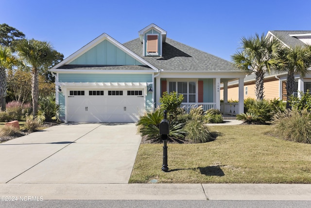 view of front of home featuring covered porch, board and batten siding, a front yard, concrete driveway, and an attached garage