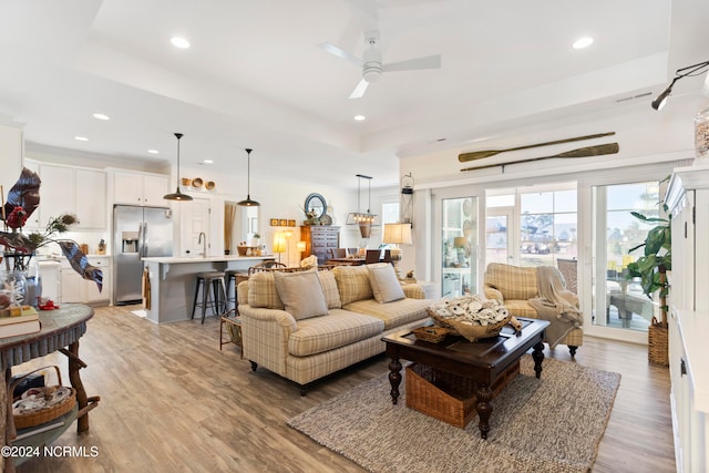 living area featuring recessed lighting, a raised ceiling, and light wood-style floors