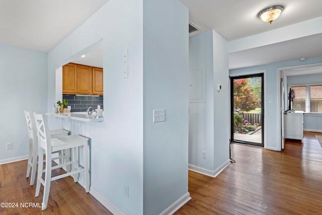 kitchen with a kitchen breakfast bar, hardwood / wood-style flooring, sink, and tasteful backsplash