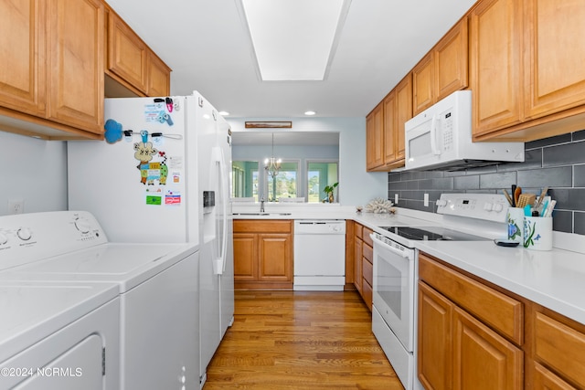 kitchen with washer and dryer, light hardwood / wood-style flooring, a notable chandelier, decorative light fixtures, and white appliances