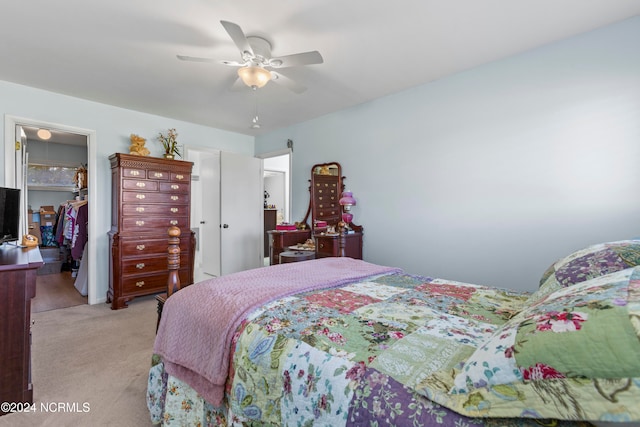 bedroom with light carpet, a closet, a walk in closet, and ceiling fan