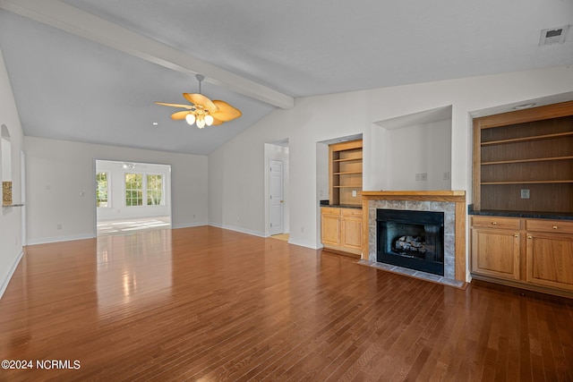 unfurnished living room with hardwood / wood-style floors, lofted ceiling with beams, a tile fireplace, and ceiling fan