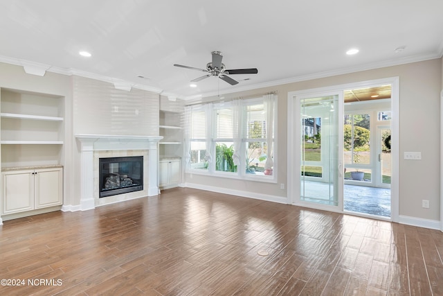 unfurnished living room featuring built in shelves, hardwood / wood-style flooring, and a healthy amount of sunlight