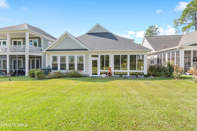 back of property with a balcony, central AC, a yard, and a sunroom