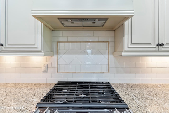 kitchen with backsplash, light stone countertops, exhaust hood, and stove