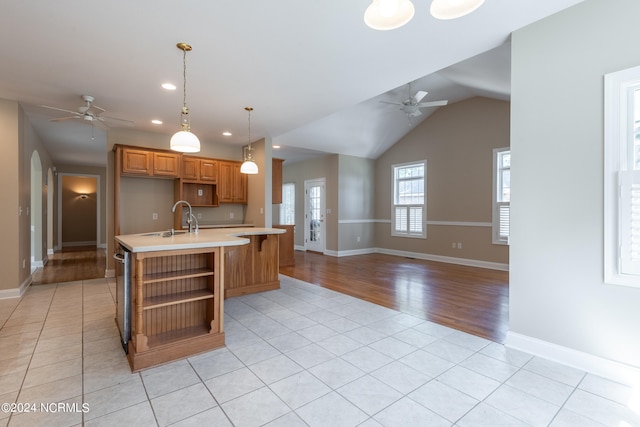 kitchen featuring sink, hanging light fixtures, ceiling fan, light hardwood / wood-style floors, and a center island with sink