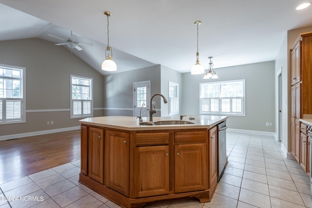 kitchen with a sink, light countertops, light tile patterned flooring, dishwasher, and hanging light fixtures