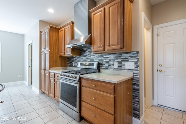 kitchen with stainless steel range with gas stovetop, light tile patterned flooring, wall chimney range hood, and tasteful backsplash