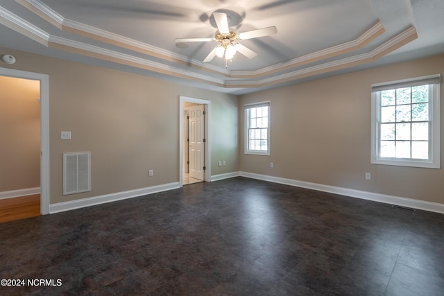 empty room with visible vents, ceiling fan, crown molding, and a tray ceiling