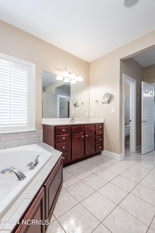 full bath featuring tile patterned floors, a garden tub, vanity, and baseboards