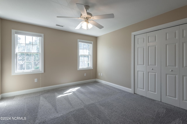 unfurnished bedroom with multiple windows, a closet, carpet flooring, and ceiling fan