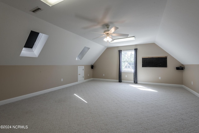 additional living space featuring lofted ceiling with skylight, ceiling fan, light carpet, and baseboards