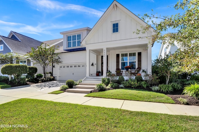 view of front of home with covered porch, a garage, and a front lawn