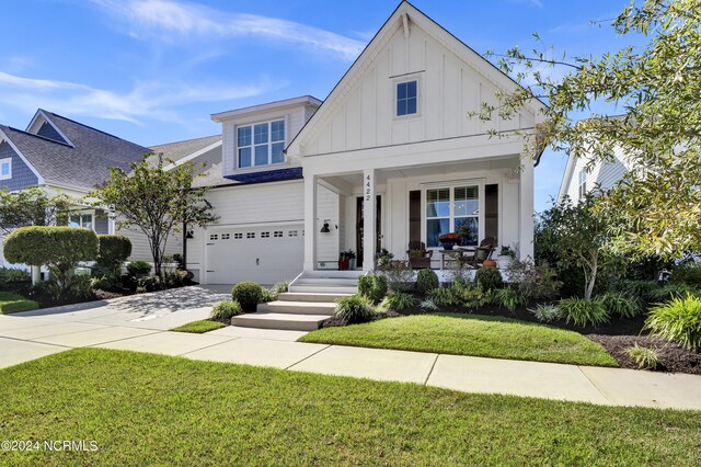 4422 Old Towne St, Wilmington, NC 28412 - modern farmhouse style home featuring a front lawn, concrete driveway, board and batten siding, a porch, and a garage