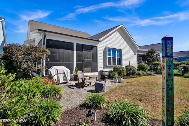 rear view of house featuring a yard, a patio, and a sunroom