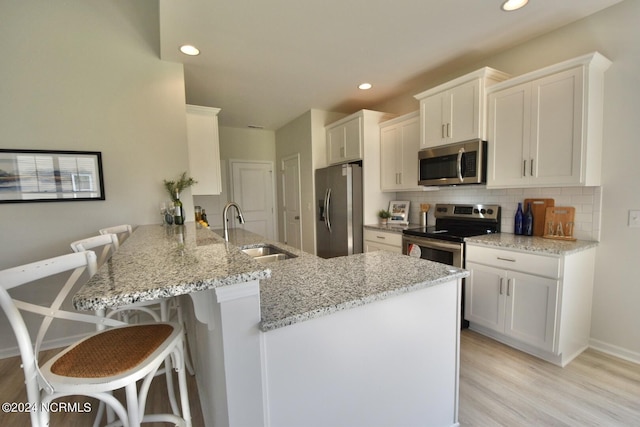 3965 Pepperberry Ln, Southport, NC 28461 - kitchen featuring appliances with stainless steel finishes, a kitchen breakfast bar, a peninsula, decorative backsplash, and white cabinets