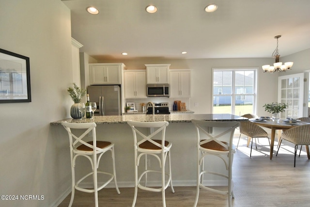3965 Pepperberry Ln, Southport, NC 28461 - kitchen with stainless steel appliances, light stone counters, decorative backsplash, white cabinetry, and a chandelier