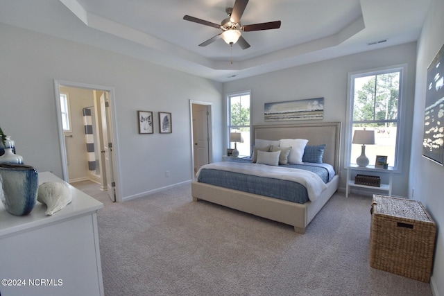3965 Pepperberry Ln, Southport, NC 28461 - bedroom with a tray ceiling, light colored carpet, ceiling fan, and connected bathroom