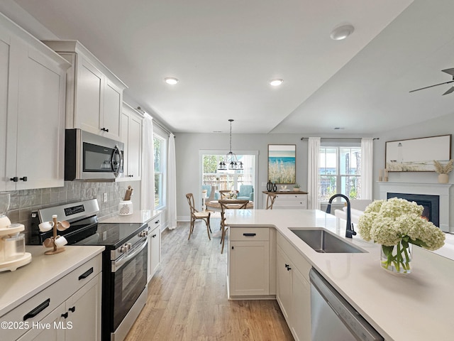 3965 Pepperberry Ln, Southport, NC 28461 - kitchen with appliances with stainless steel finishes, light wood-style flooring, light countertops, decorative backsplash, and white cabinetry