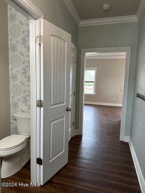 corridor with dark wood-type flooring and ornamental molding