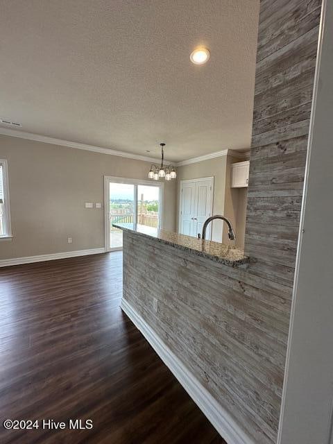 kitchen with dark wood-type flooring, white cabinets, hanging light fixtures, light stone counters, and a chandelier