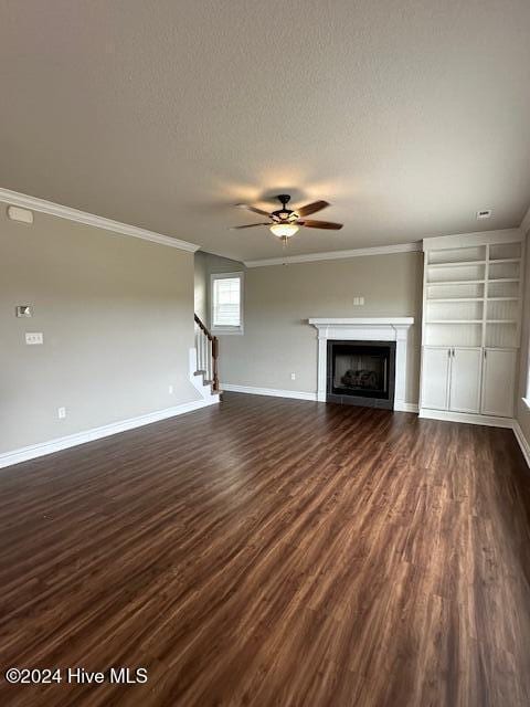 unfurnished living room featuring a textured ceiling, dark hardwood / wood-style floors, ceiling fan, and crown molding