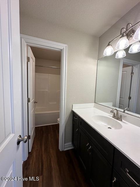 full bathroom featuring hardwood / wood-style floors, vanity, toilet, a textured ceiling, and shower / bath combination